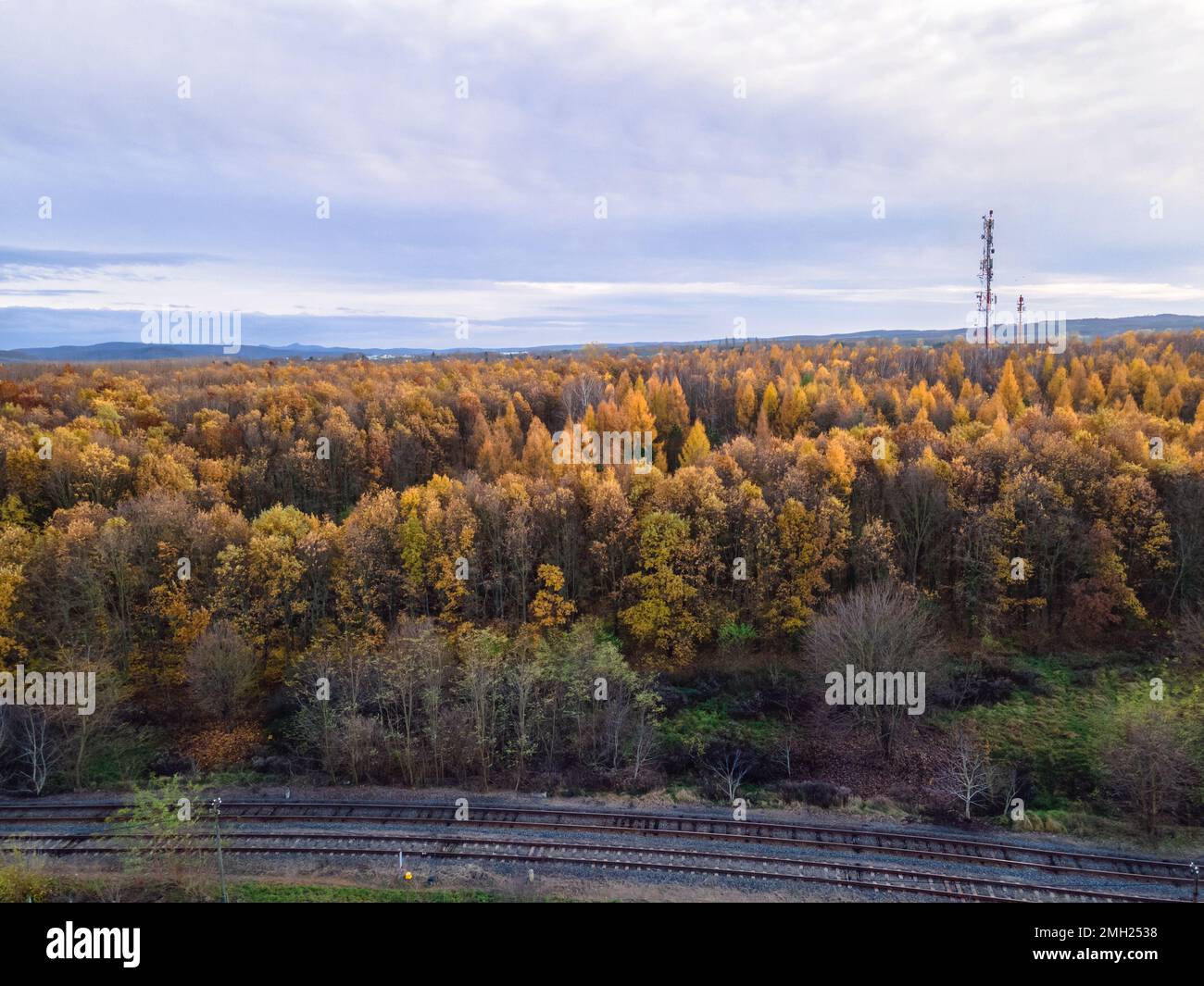 Ripresa aerea di un'area boscosa nei colori autunnali, binari ferroviari in fondo alla foto, Balassagyarmat, Ungheria Foto Stock