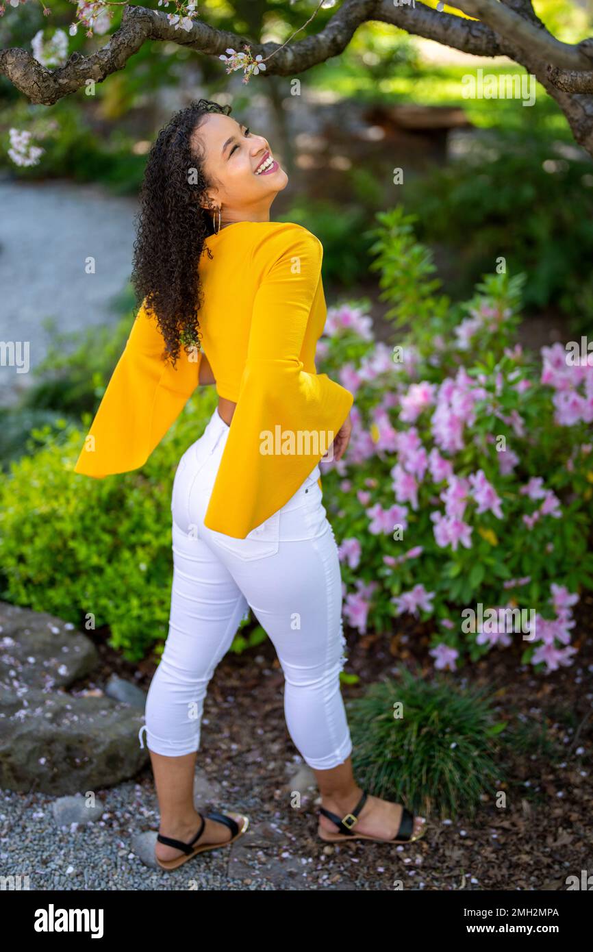 Down Angle Portrait of Happy Young African American Woman in a fioritura Japanese Style Garden a Springtime - Spring Foto Stock