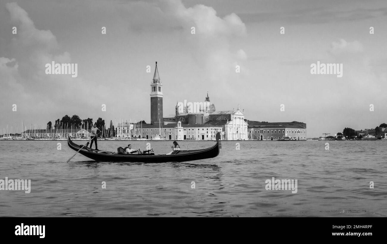 Una gondola passa davanti alla Basilica di San Giorgio maggiore sulla Laguna di Venezia Foto Stock