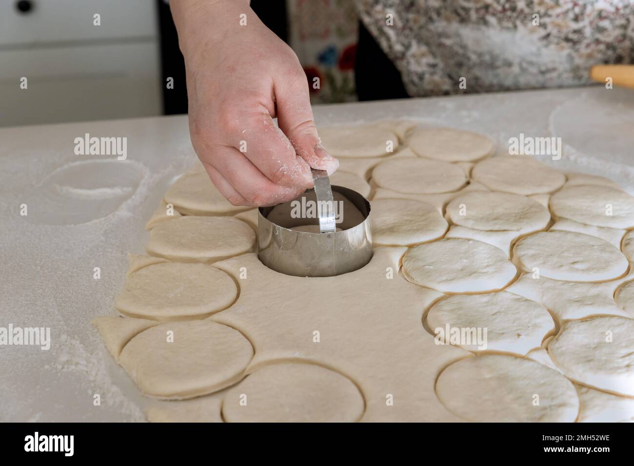 L'impasto a ciambella è preparato da impasto crudo è tagliato in pezzi rotondi con il perno di laminazione sul tavolo da forno in forno Foto Stock