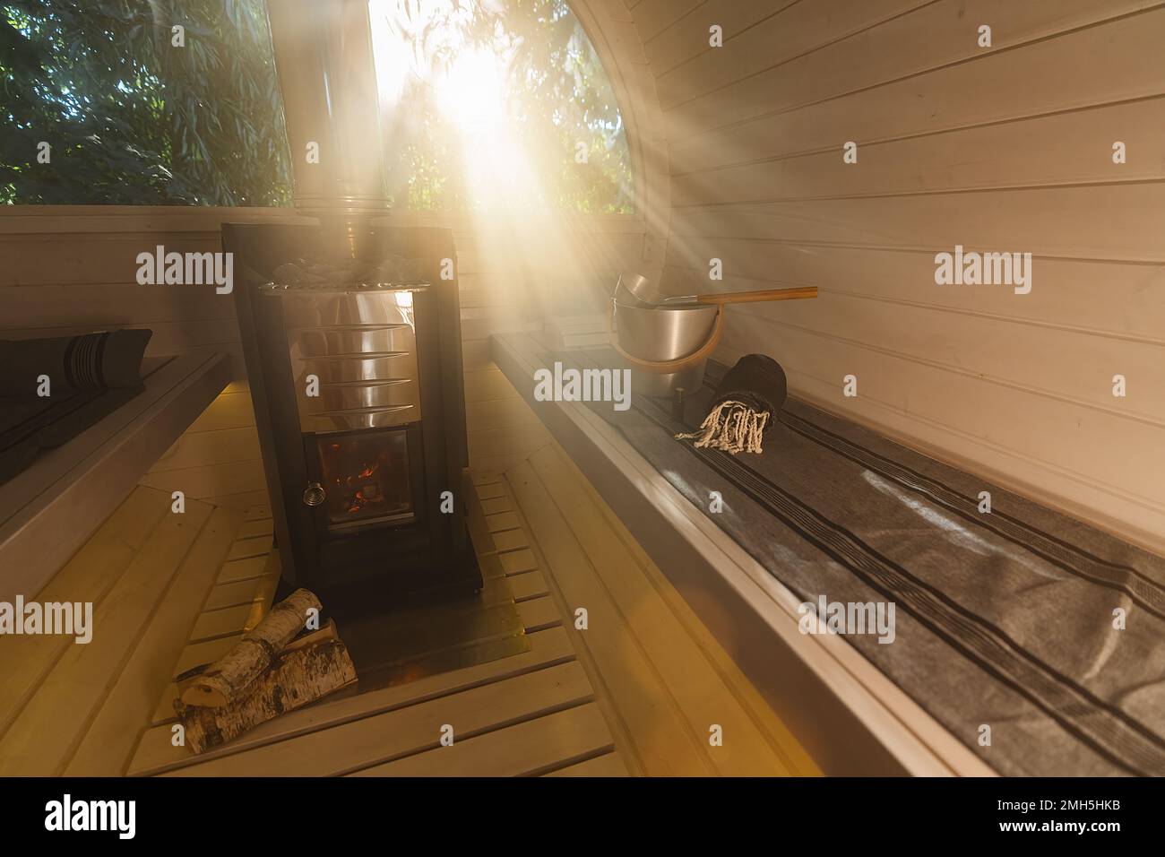 All'interno di una calda sauna finlandese wodden barile con pietre calde e vapore con raggi di sole in estate in Norvegia. Bagno a temperatura calda. Tradizionale Foto Stock