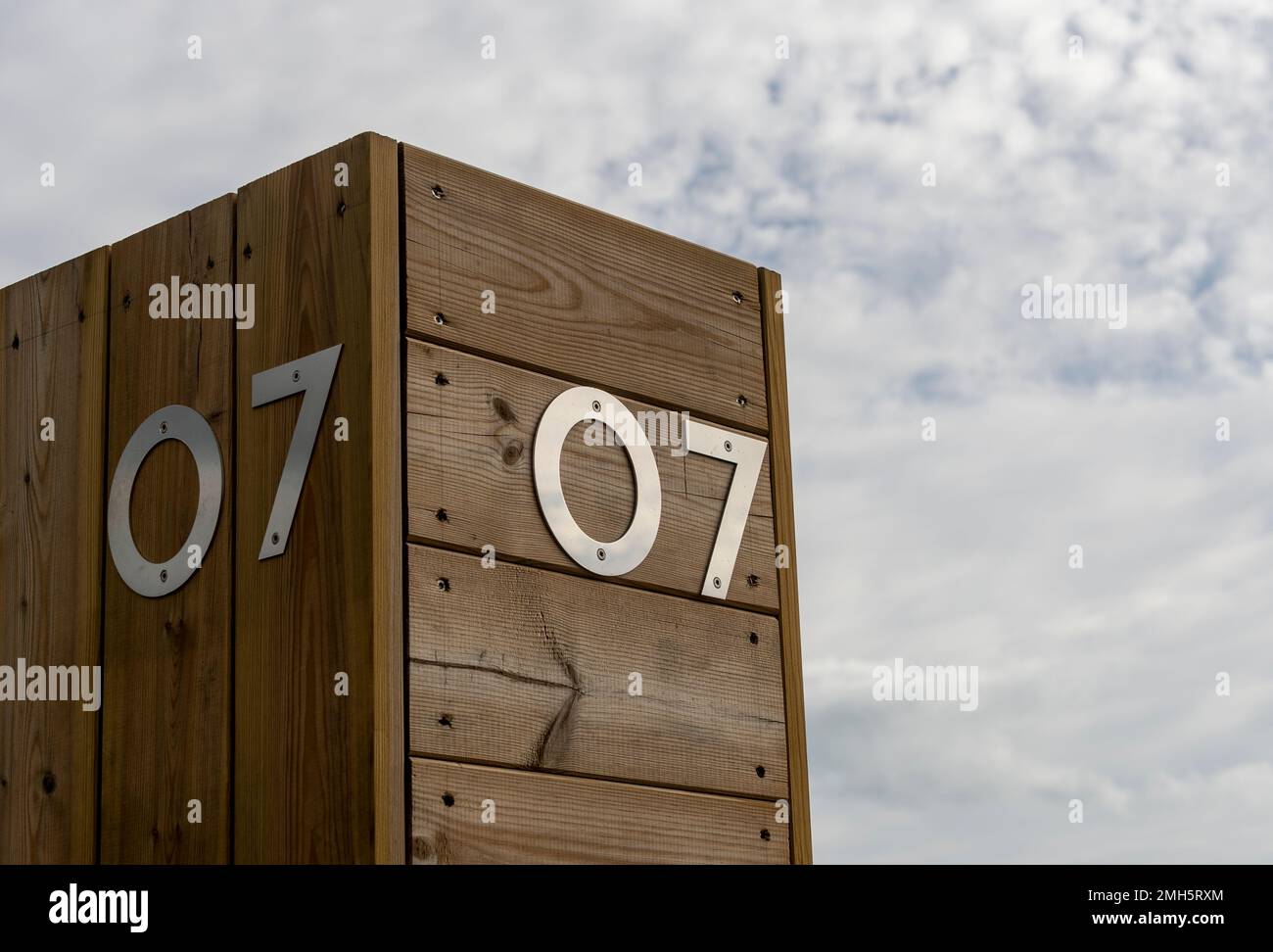 Il numero sette in acciaio inossidabile su uno sfondo di legno contro il cielo. 07 Foto Stock