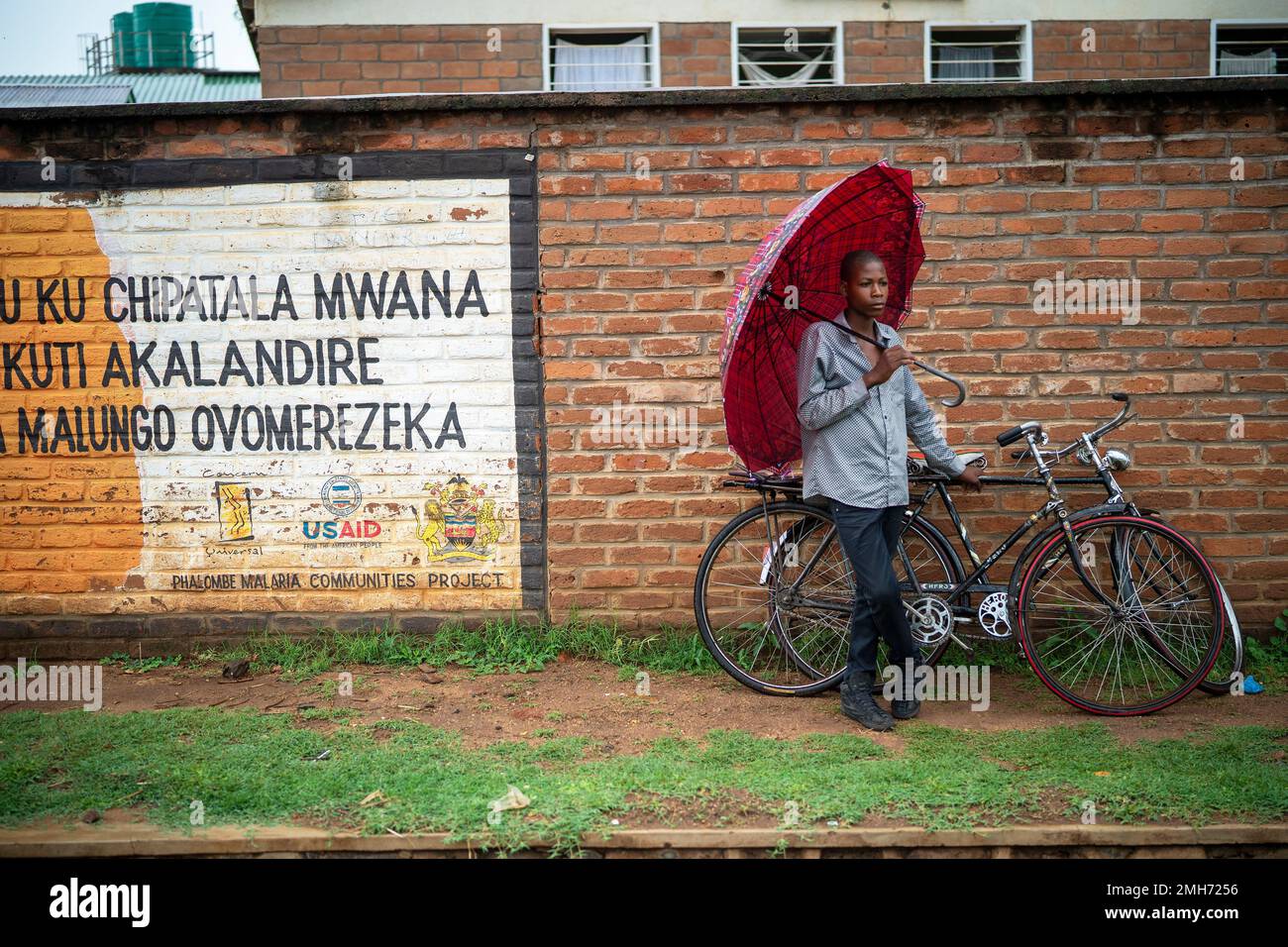 In this photograph taken Tuesday Dec. 10, 2019, A man stands outside the health clinic in the village of Migowi, Malawi. Malawi is rolling out an unusual pilot vaccination program against Malaria, one of history's deadliest and most stubborn disease. Parents in Malawi as well as Kenya and Ghana, are being asked to put faith in a series of injections that are only about 40% effective. (AP Photo/Jerome Delay) Foto Stock