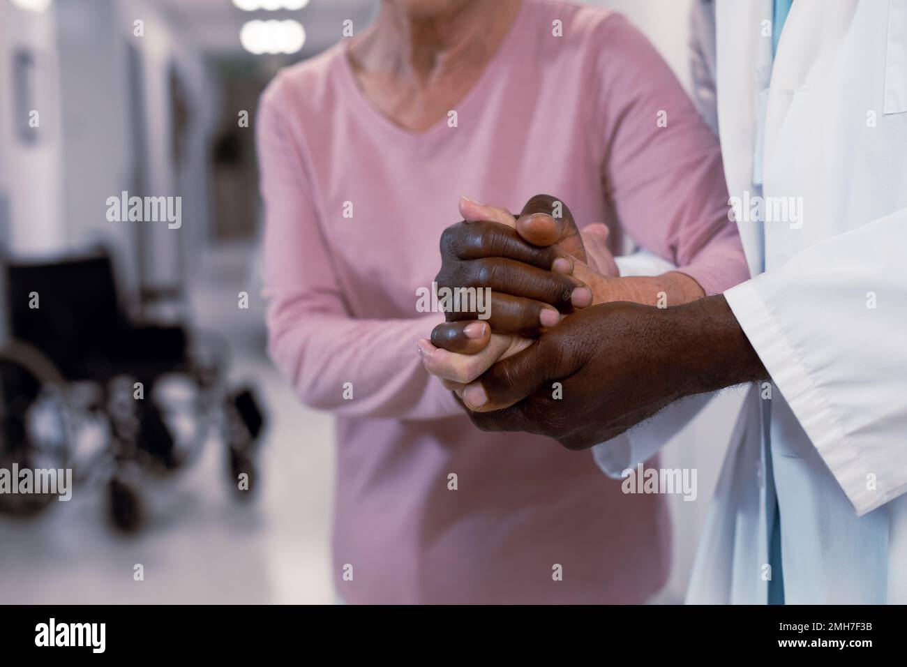 Primo piano del medico afro-americano e del paziente caucasico senior che tiene le mani Foto Stock