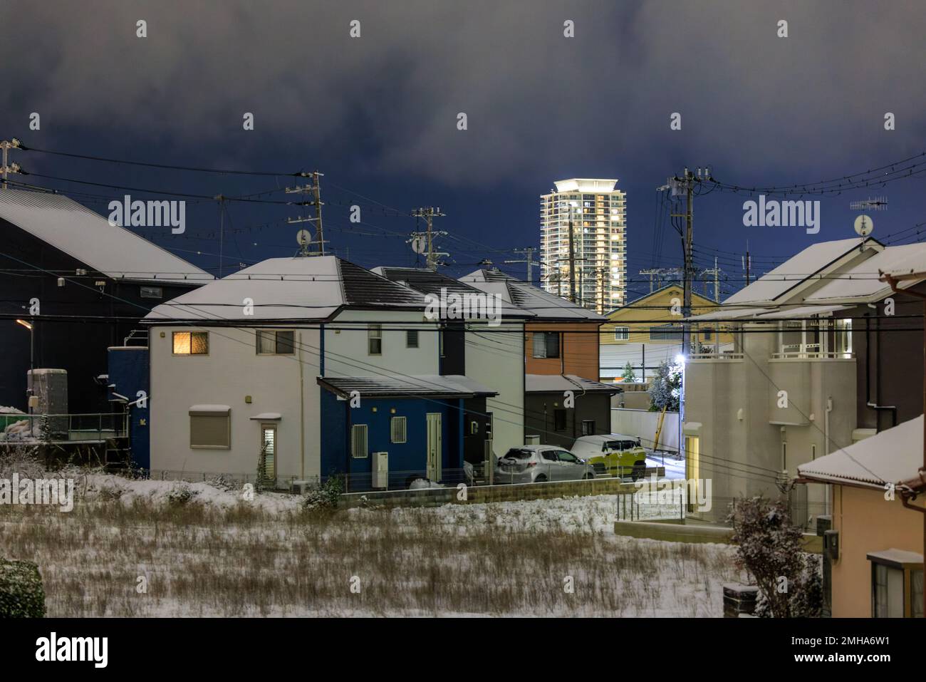 Case suburbane coperte di neve con lontano appartamento di lusso torre di notte Foto Stock