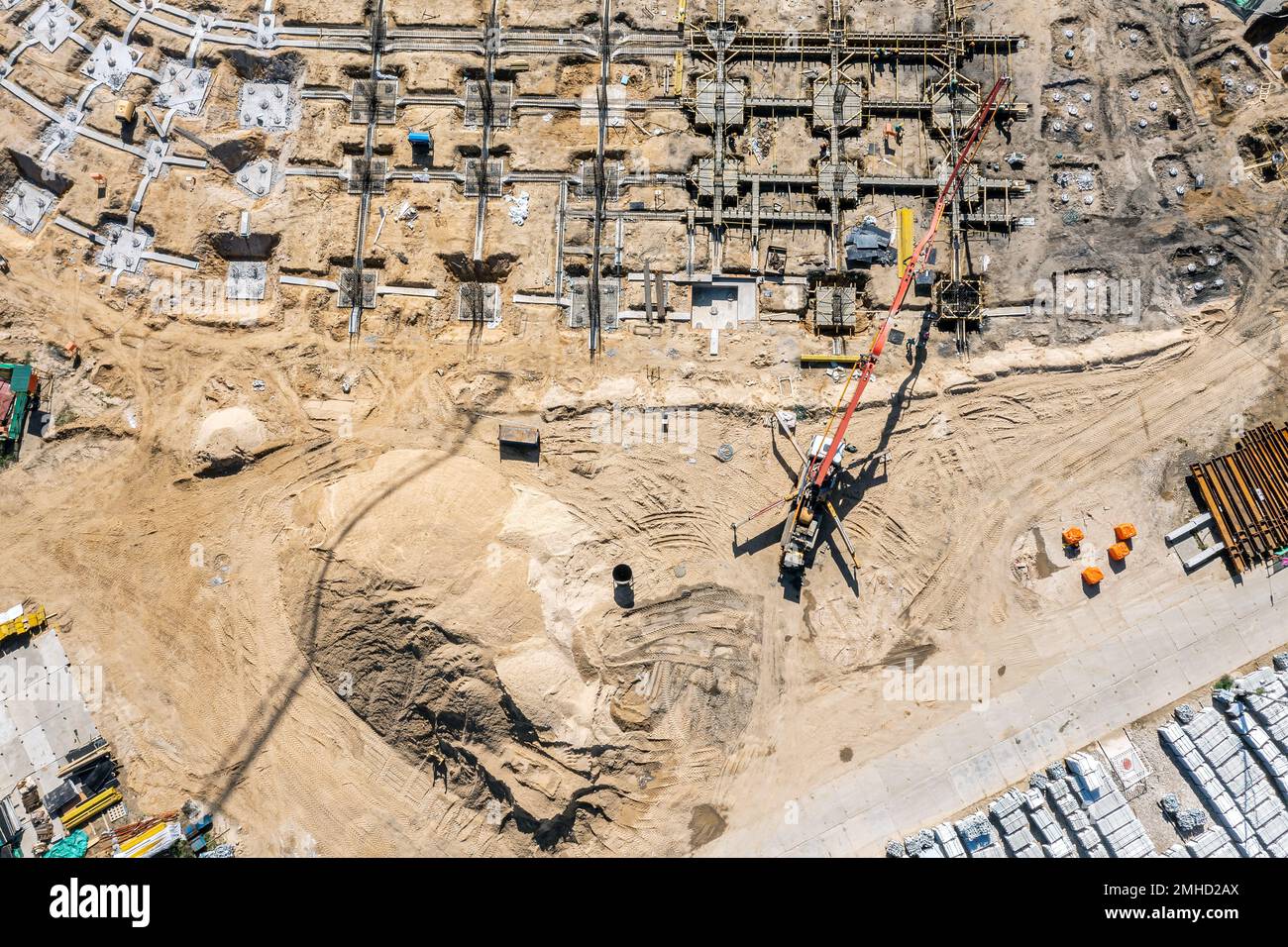 operai di costruzione che versano calcestruzzo bagnato in fondazione da macchina di pompa di calcestruzzo. vista aerea dall'alto del cantiere. Foto Stock