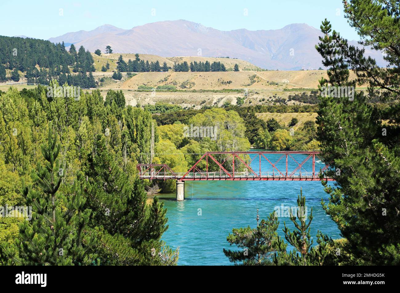 Il ponte rosso tra gli alberi - fiume Clutha - Nuova Zelanda Foto Stock