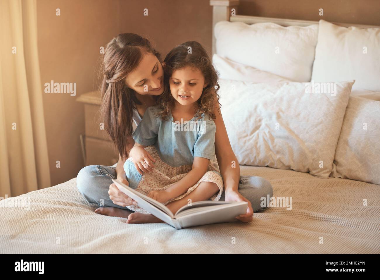 Voglio essere una principessa quando . Sono cresciuto. una madre e una figlia felici a casa leggendo un libro di storia sul letto. Foto Stock