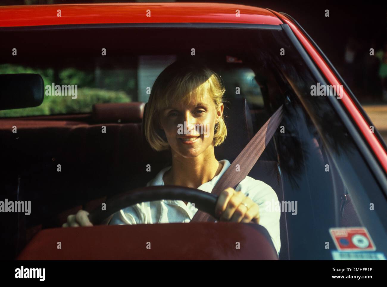 1990 STORICA DONNA CONDUCENTE CHE INDOSSA LA CINTURA DI SICUREZZA IN AUTO NORDAMERICANA Foto Stock