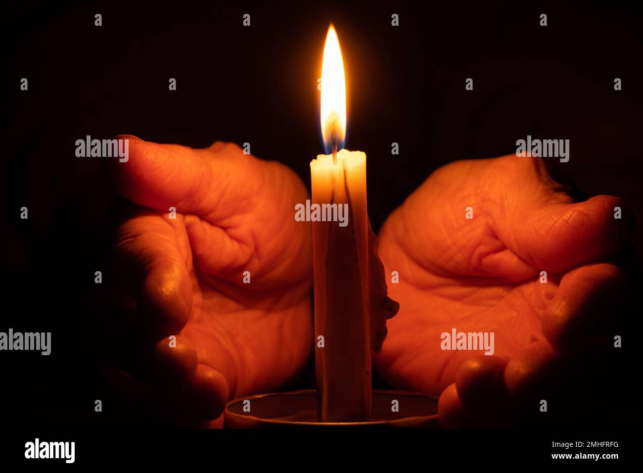 le mani della vecchia donna e la fiamma della candela al buio, la luce della candela, il lutto, la candela al buio Foto Stock