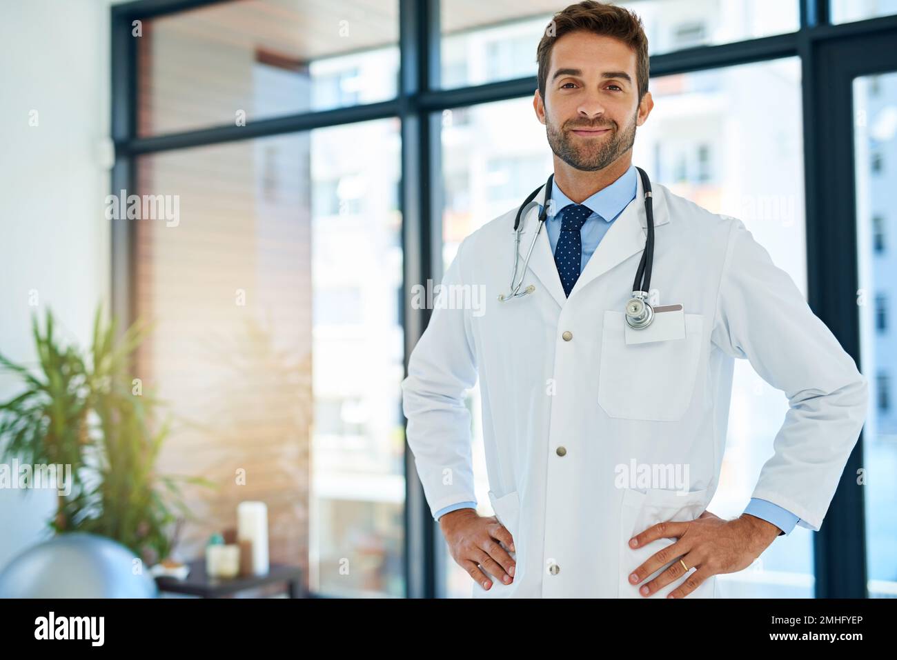 Im il meglio a quello che faccio. Ritratto di un giovane medico fiducioso in posa con le mani sui fianchi in un ospedale. Foto Stock