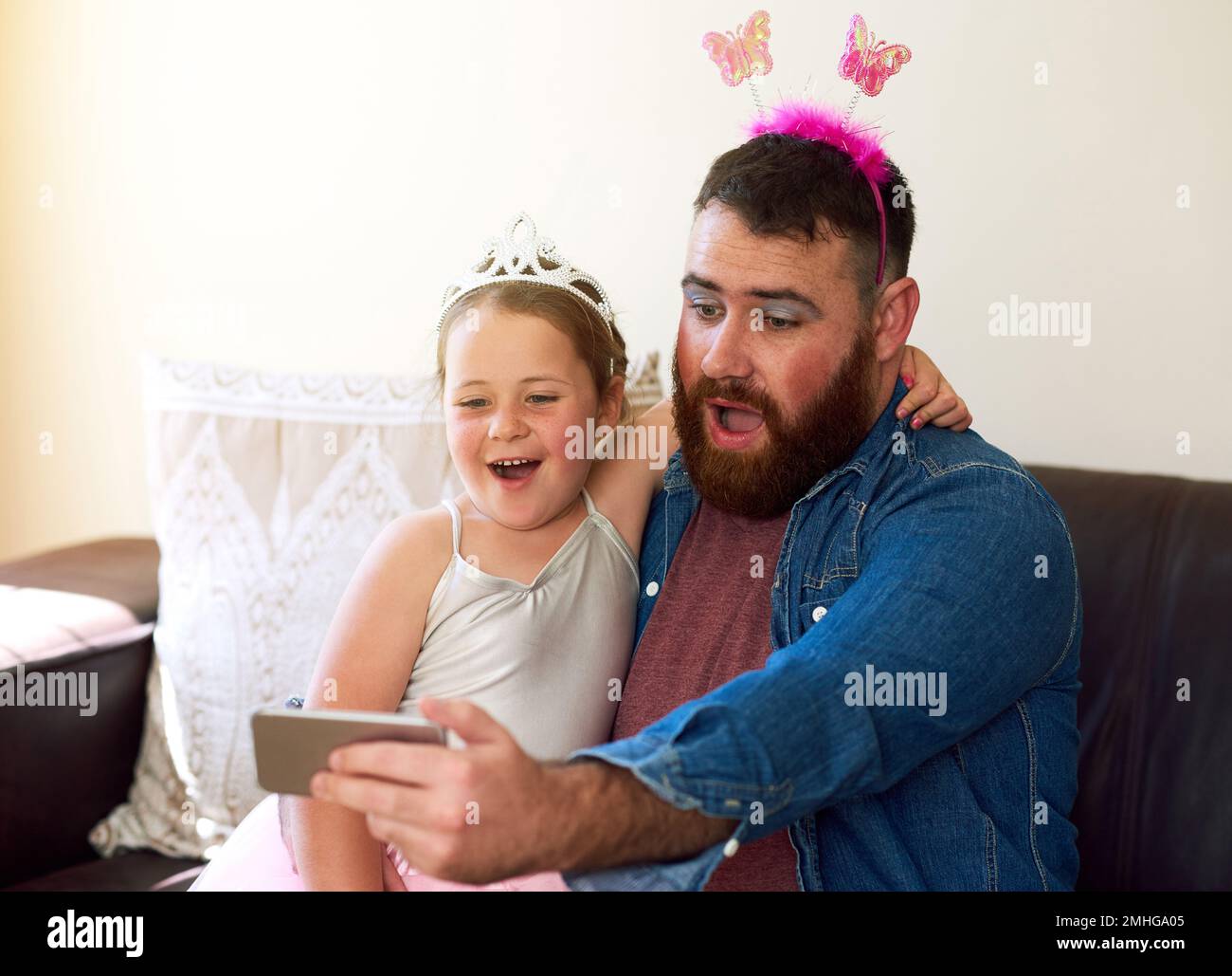 Ottenere un makeover significa il relativo tempo del selfie. una ragazza adorabile che gioca vestire e prendere selfie con suo padre a casa. Foto Stock