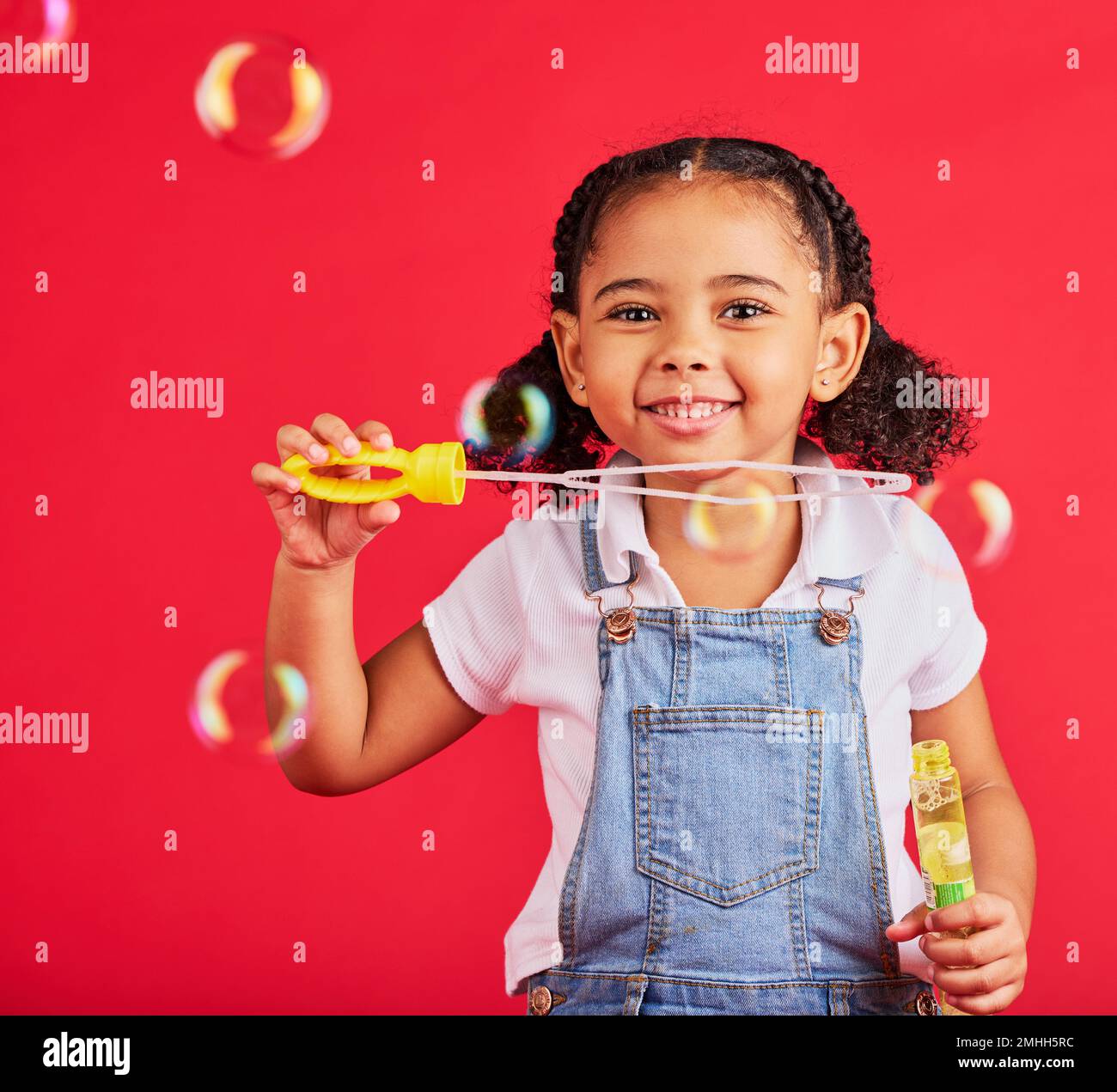 Bambina, ritratto o bolle giocando su sfondo rosso isolato in coordinazione occhio mano, attività per bambini o gioco divertente. Sorridi, felice o bambino e. Foto Stock