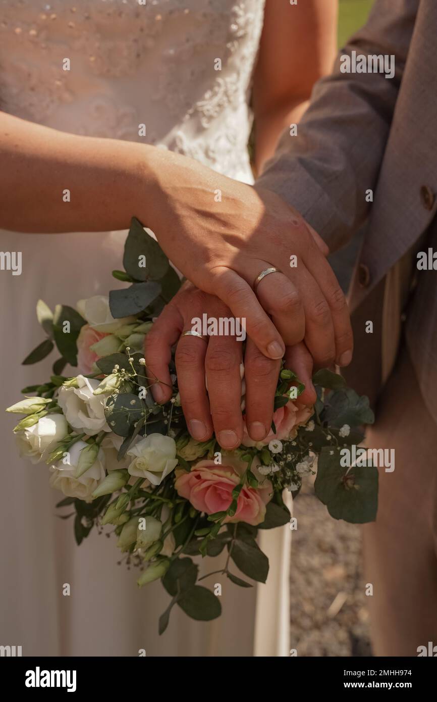 Le mani dello sposo e della sposa sul mazzo di nozze Foto Stock