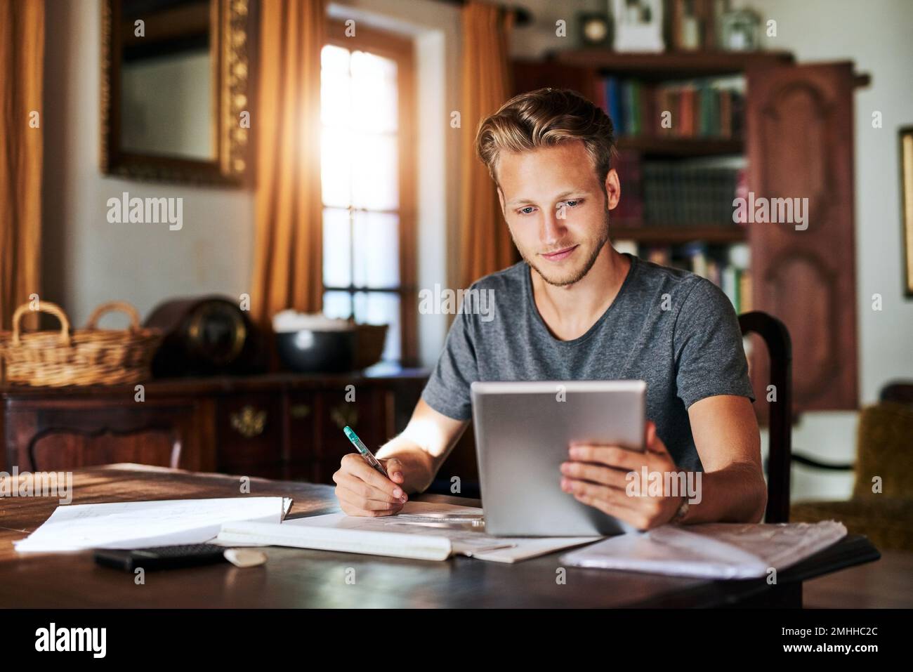 Tutto ciò di cui avete bisogno sono le risorse giuste. un giovane uomo che usa un tablet digitale mentre lavora a un progetto a casa. Foto Stock