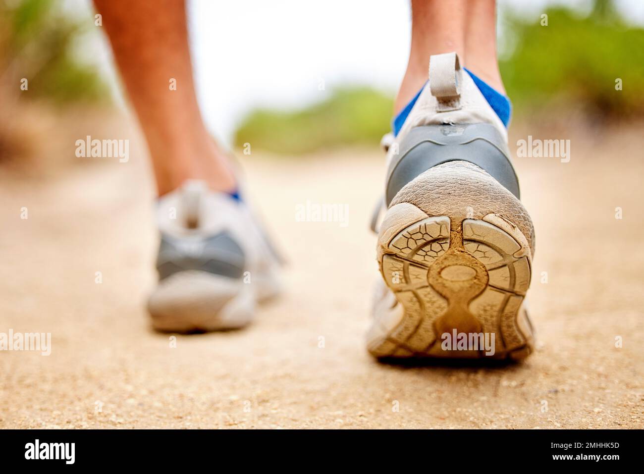 Fitness, scarpe e sport persona che cammina, corsa e l'uomo di allenamento sul percorso. Primo piano posteriore di runner, piedi e sneakers a terra per l'esercizio fisico, parco Foto Stock