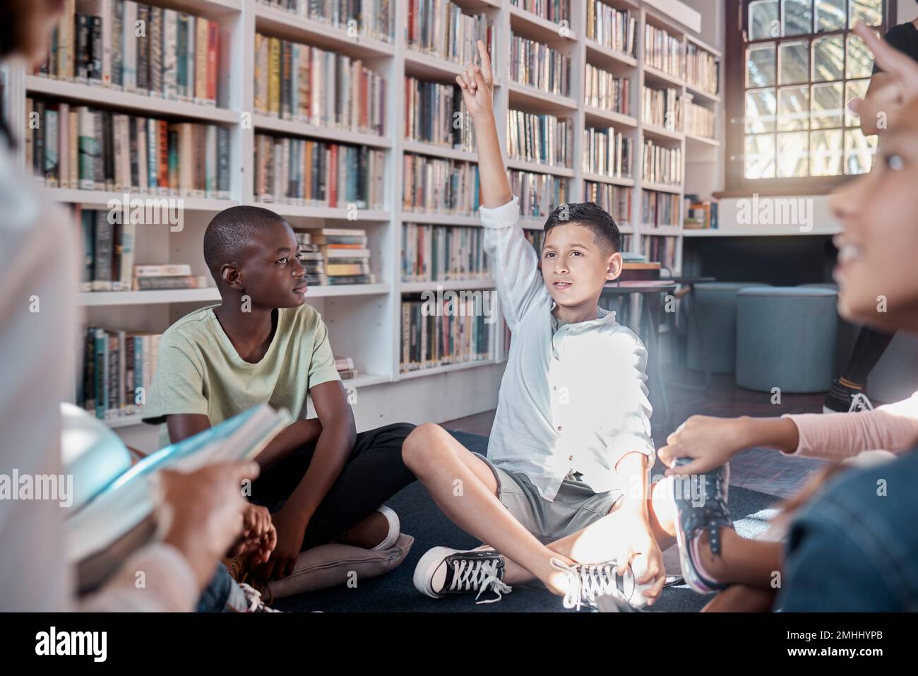 Insegnante, lettore o studente con domande in aula o biblioteca per lo sviluppo dell'apprendimento. Mani in su, narrazione o bambini che ascoltano e intelligenti Foto Stock