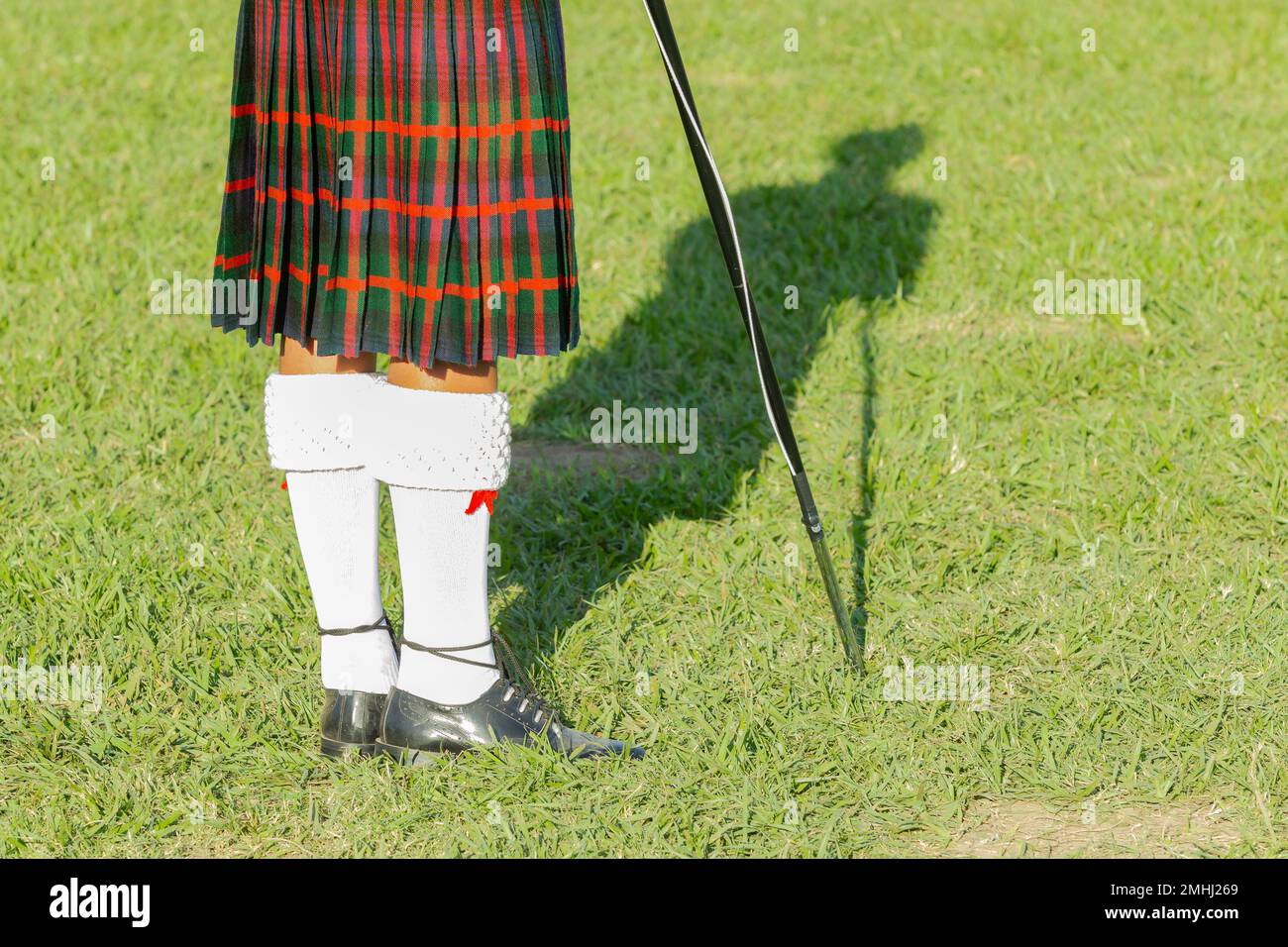 Banda scozzese musicista tamburo principali colori kilt a Highland giochi una vista posteriore fotografia all'aperto campo luogo estate blu cielo giorno. Foto Stock
