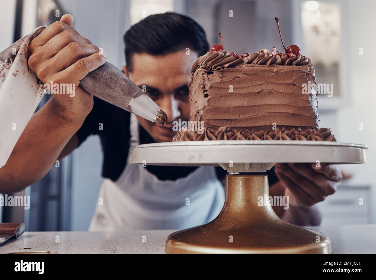 Piping, chef e panettiere cottura di una torta al cioccolato in cucina o pasticceria cuoco preparazione di una ricetta dolce. Cibo, dessert e cuoco preparare un dolce Foto Stock