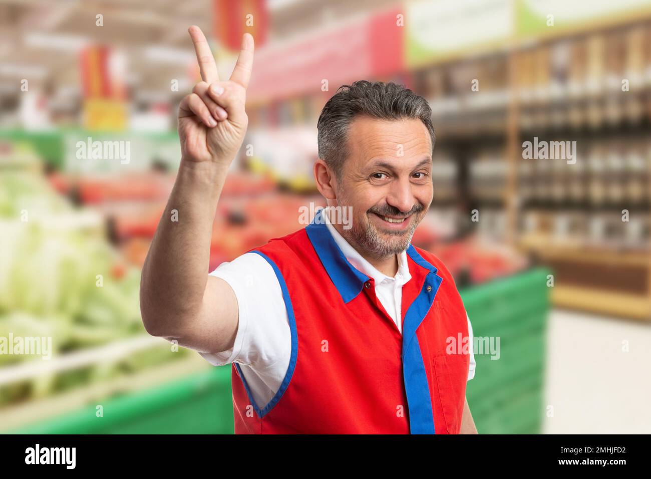 Un venditore sorridente che mostra la pace cantare con le dita come tutto il buon concetto Foto Stock