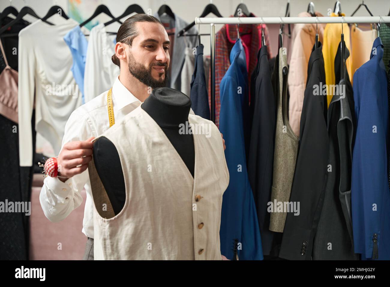 Gioioso sarto provando su nuovo pezzo di abbigliamento su manichino Foto Stock