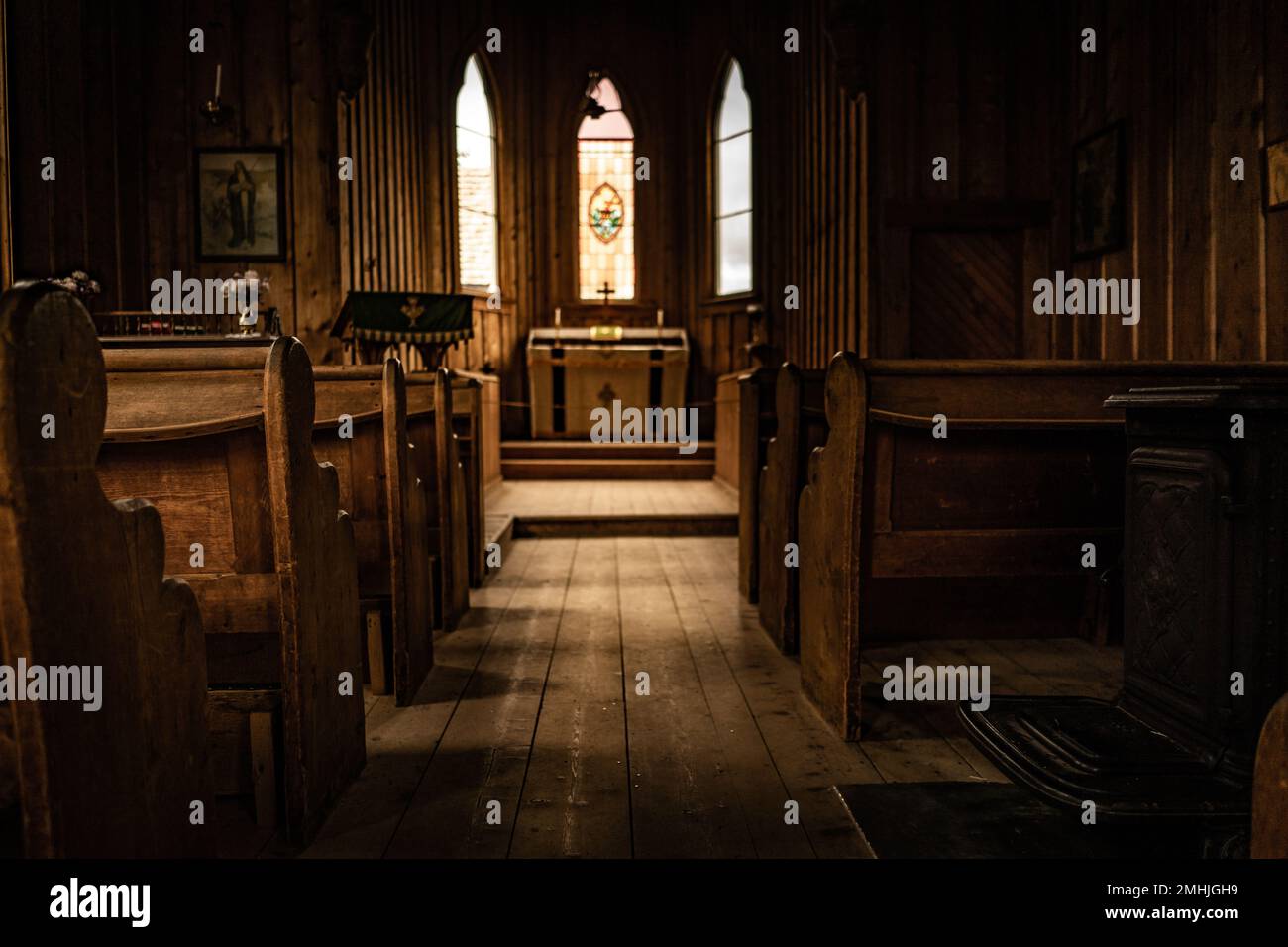 Un interno in legno di una chiesa con sedie di zampa e un altare Foto Stock
