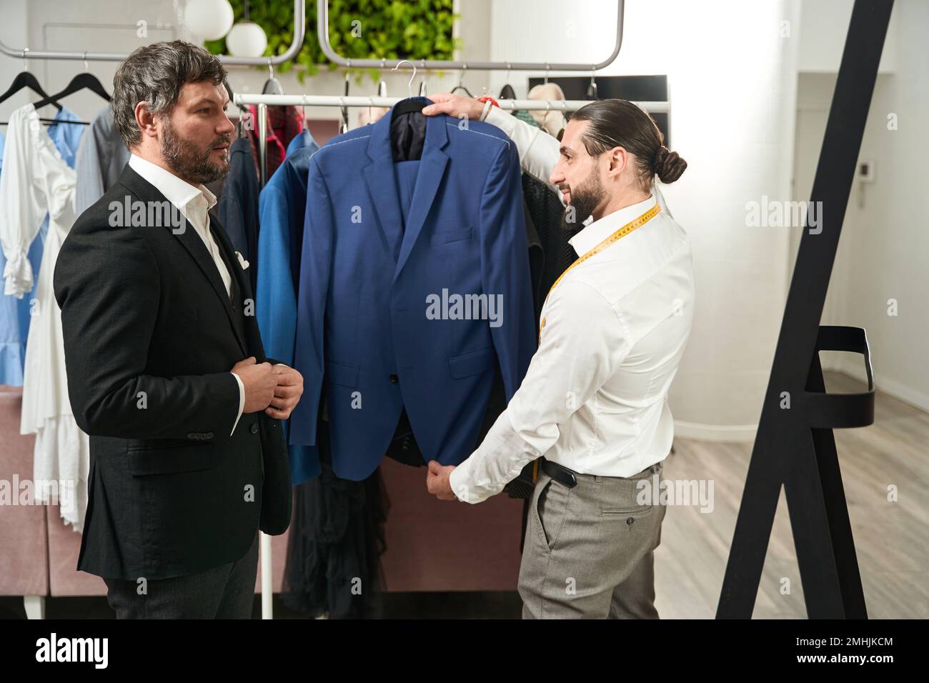 Cliente che controlla la vestibilità del suo abito personalizzato in studio Foto Stock