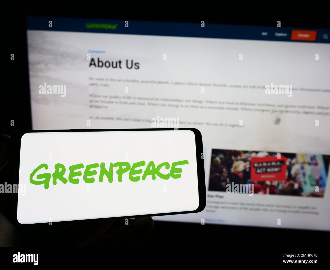 Persona che tiene il telefono cellulare con il logo della campagna ambientale rete Greenpeace sullo schermo di fronte alla pagina web. Messa a fuoco sul display del telefono. Foto Stock