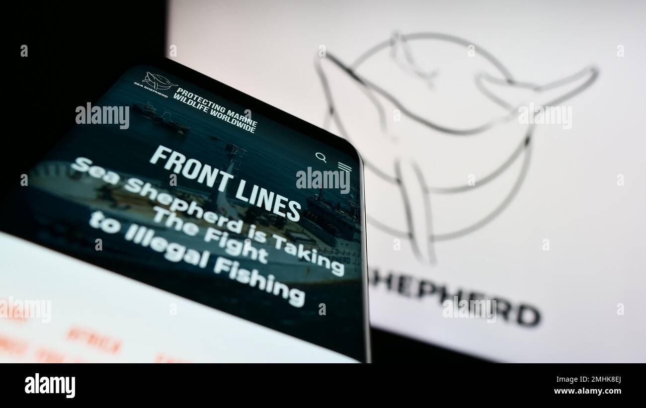 Telefono cellulare con pagina web della Sea Shepherd Conservation Society (SSCS) sullo schermo di fronte al logo. Messa a fuoco in alto a sinistra del display del telefono. Foto Stock