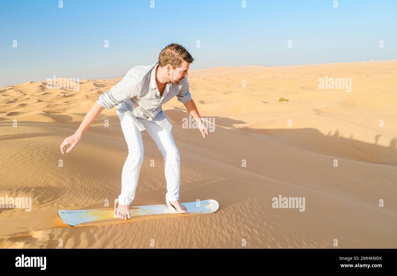 Giovani uomini che fanno surf sulle dune di sabbia di Dubai Emirati Arabi Uniti, deserto di sabbia in una giornata di sole a Dubai. Foto Stock