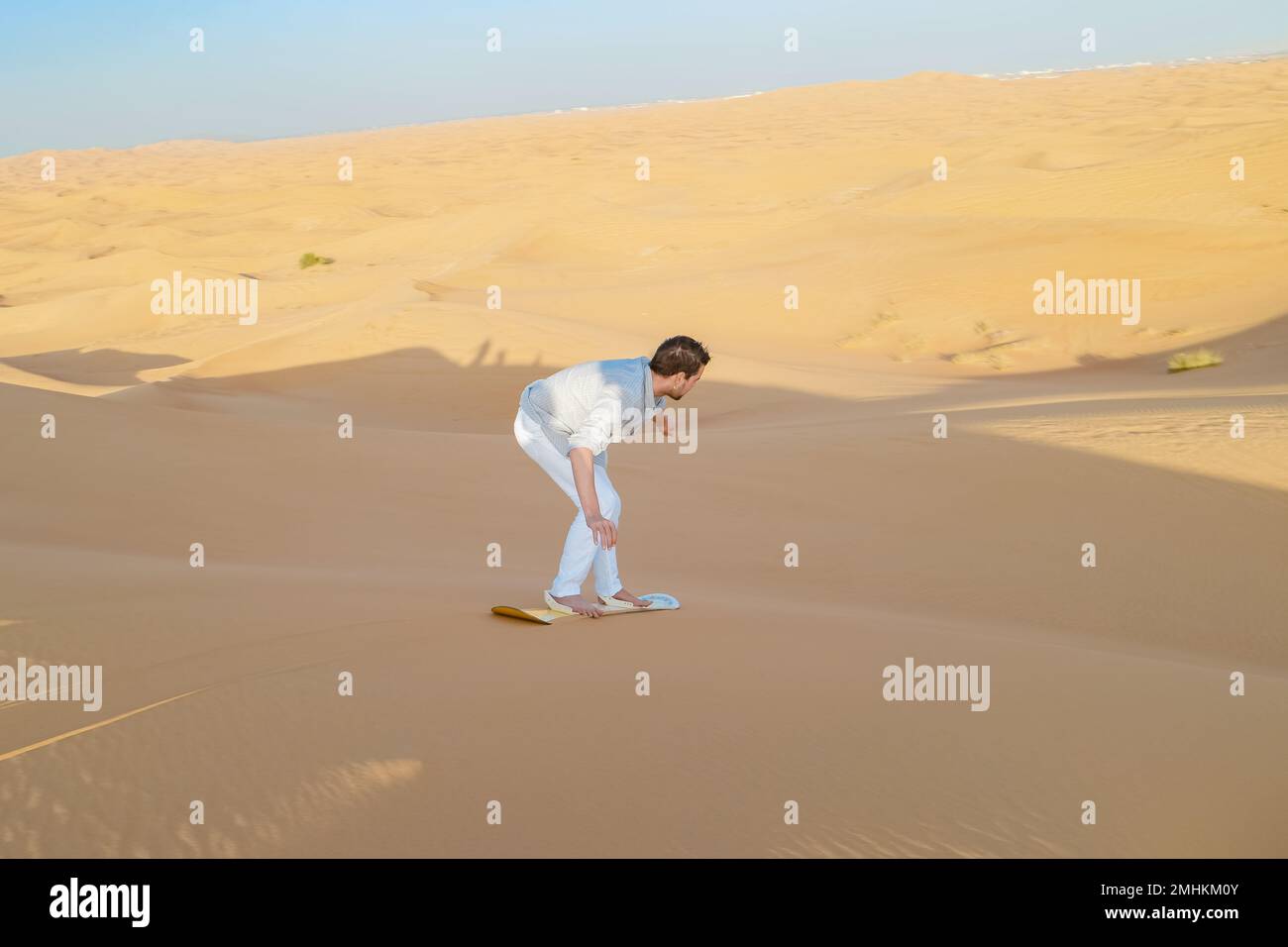 Giovani uomini che fanno surf sulle dune di sabbia di Dubai Emirati Arabi Uniti, deserto di sabbia in una giornata di sole a Dubai. Foto Stock