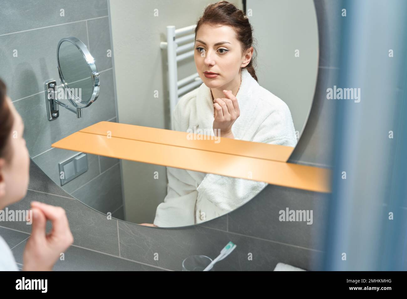 Giovane donna si trova nel bagno dell'hotel di fronte allo specchio Foto Stock