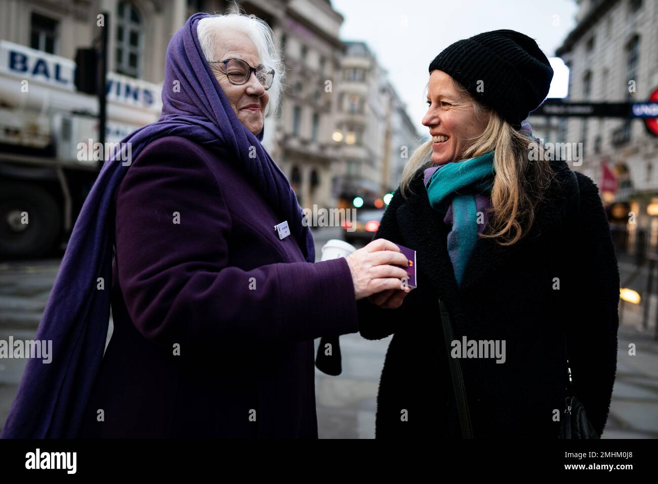 Joan Salter MBE consegna una candela commemorativa a un membro del pubblico a Piccadilly Circus, nel centro di Londra, insieme ai sopravvissuti all'Olocausto e ai successivi genocidi per celebrare il Memorial Day dell'Olocausto. Data immagine: Venerdì 27 gennaio 2023. Foto Stock
