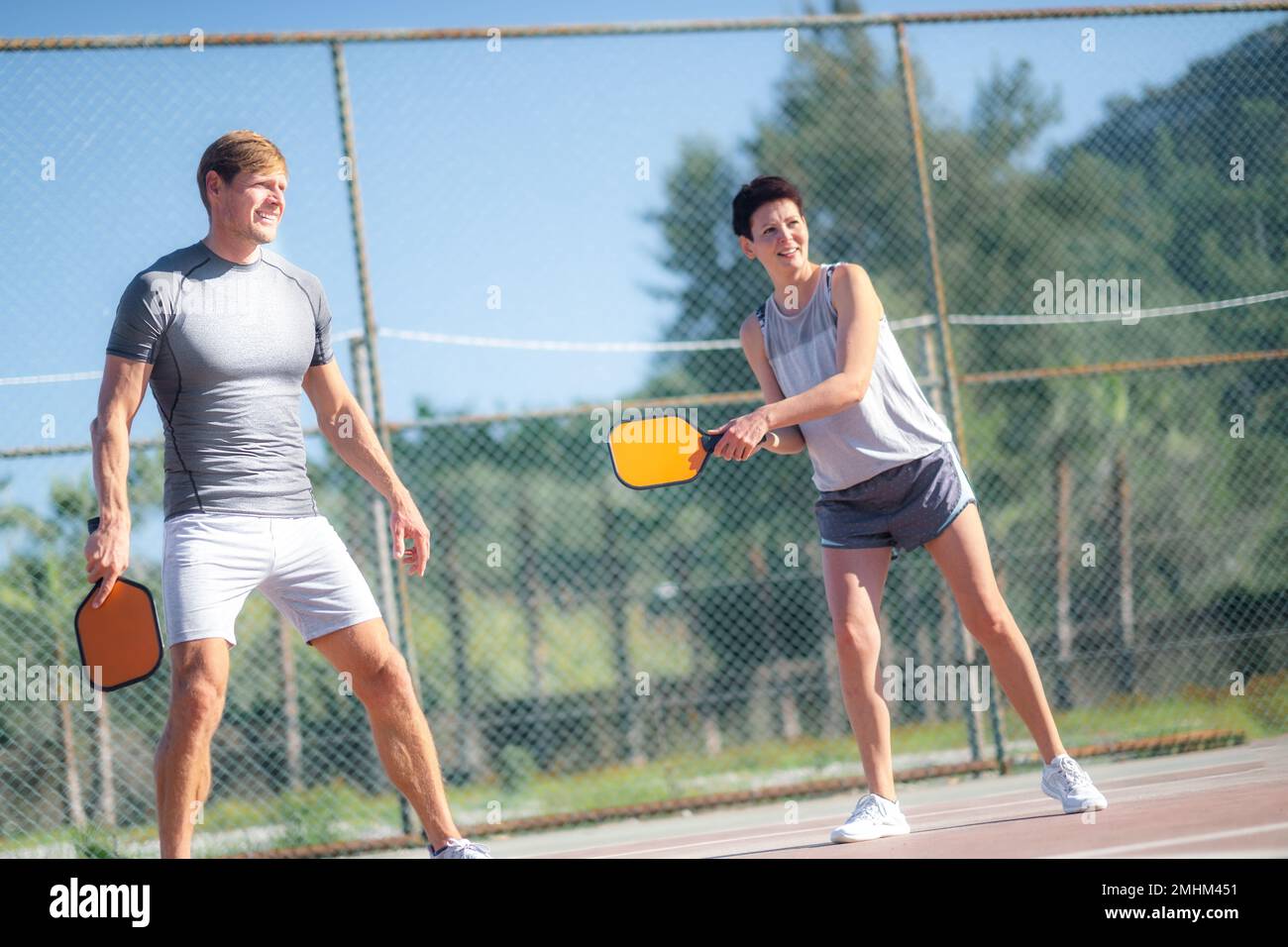 coppia che gioca a pickleball, colpire paddle paddle paddle paddle giallo palla di pickleball, attività sportive all'aperto di svago. Foto Stock