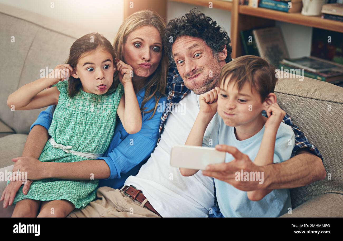 Selfie famiglia - felfie. una famiglia che prende un selfie insieme su un telefono cellulare a casa. Foto Stock