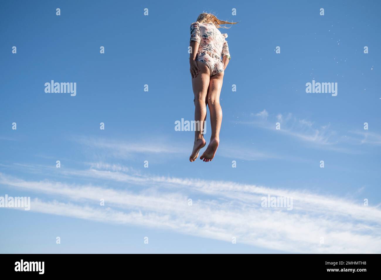 Ragazza che salta contro il cielo blu Foto Stock