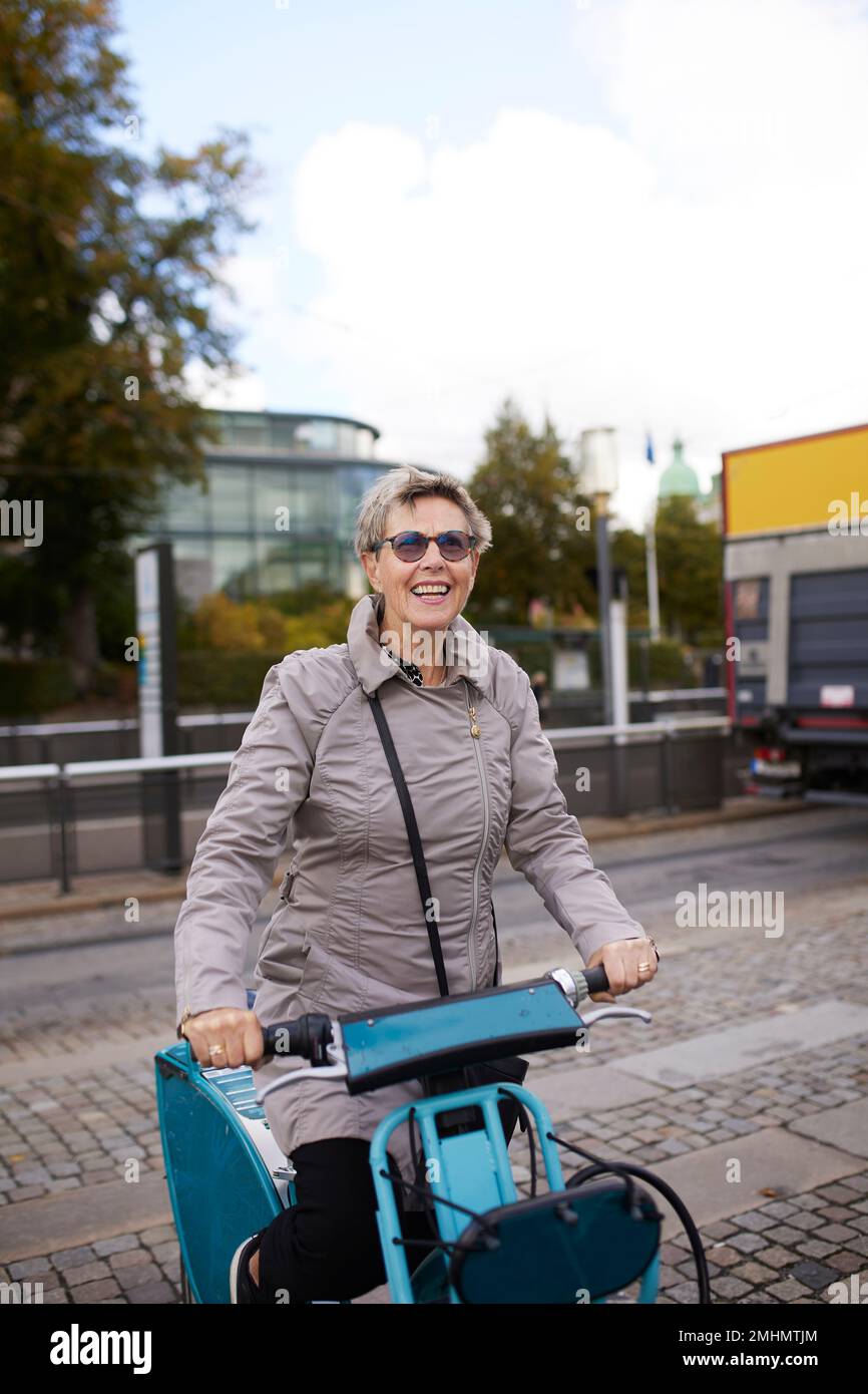 Donna felice in bicicletta da città Foto Stock