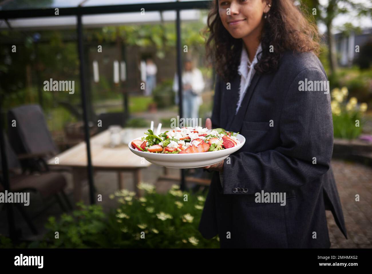 Donna sorridente che tiene il cibo sul piatto Foto Stock