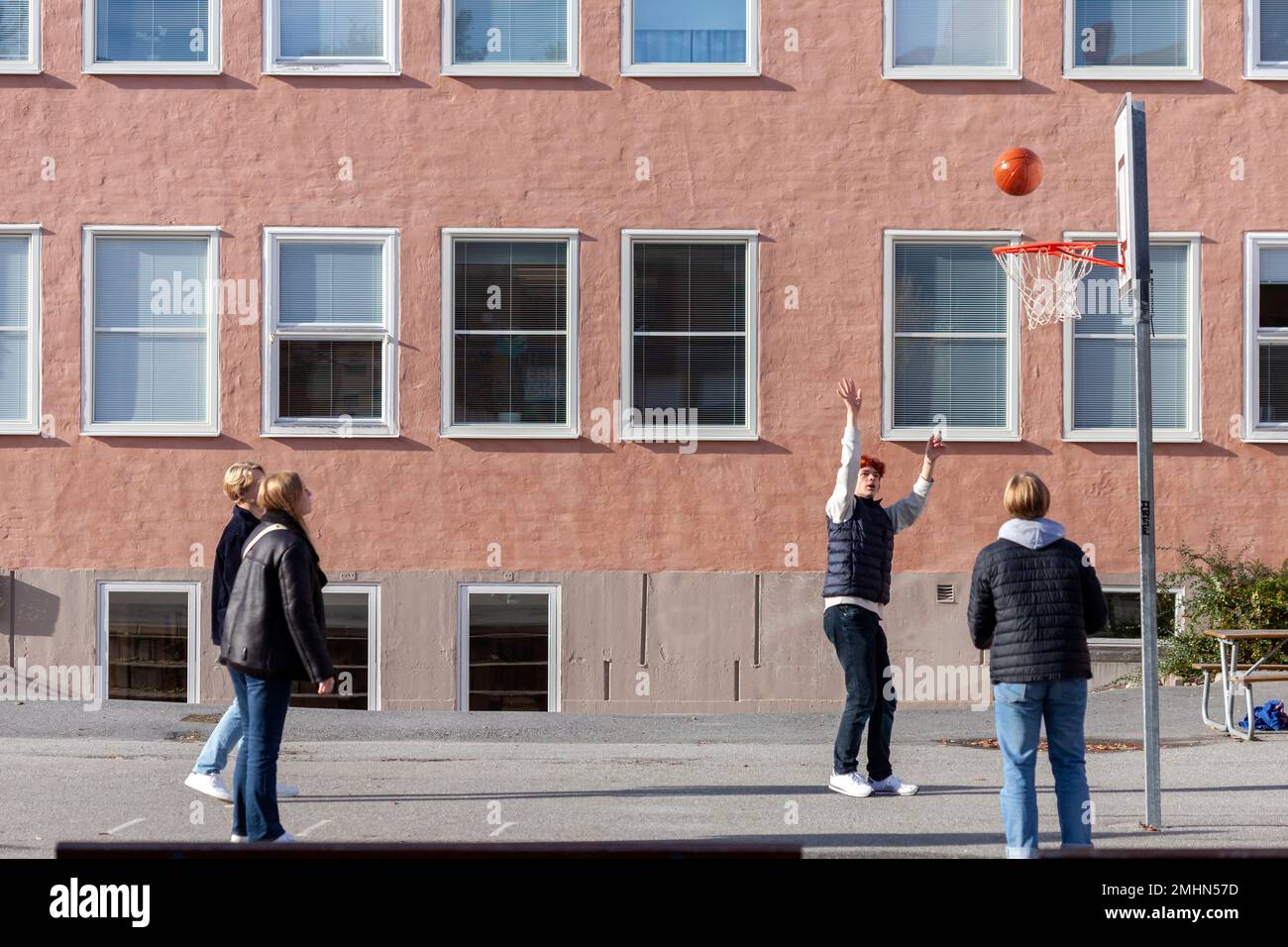 Ragazzi adolescenti che giocano a basket nel cortile della scuola Foto Stock