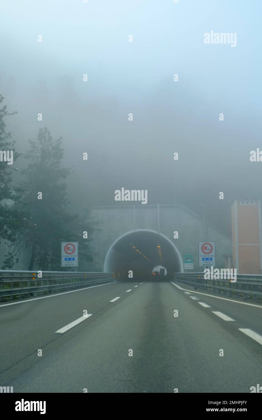 auto che guida su un'autostrada coperta da forte nebbia attraverso il tunnel in montagna. Trasporto. cattive condizioni meteorologiche Foto Stock