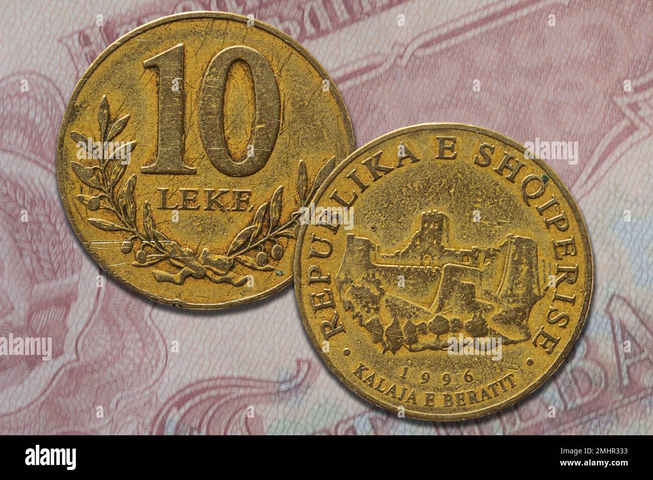 Un primo piano di una moneta di lek albanese d'oro sia dal lato opposto che da quello opposto su una banconota Foto Stock
