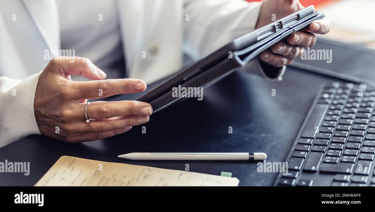 La mano di una donna d'affari sta lavorando sul tablet in ufficio. Utilizza tecnologie moderne per creare rapporti o rispondere a messaggi di posta elettronica al cliente nella stanza dell'ufficio per il multi-t Foto Stock
