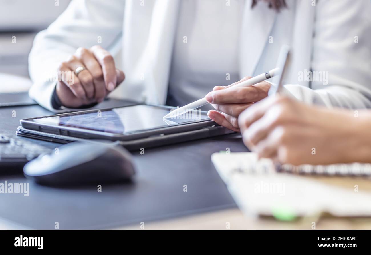 Le mani di due colleghi utilizzano un tablet digitale e un notebook. Un incontro d'affari per discutere di gestione finanziaria, contabilità o financ Foto Stock