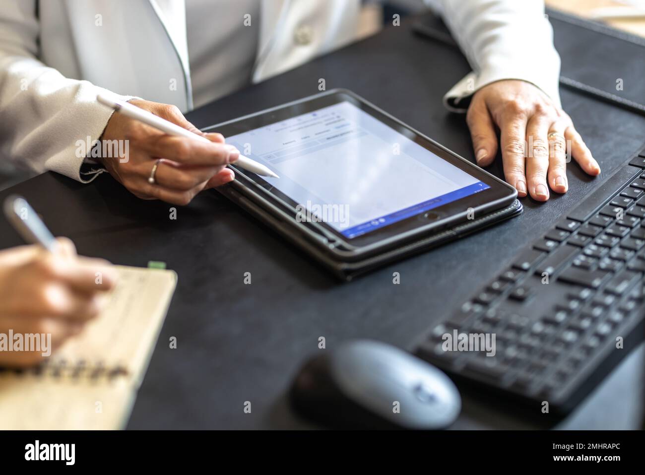 Le mani di due colleghi utilizzano un tablet digitale e un notebook. Un incontro d'affari per discutere di gestione finanziaria, contabilità o financ Foto Stock