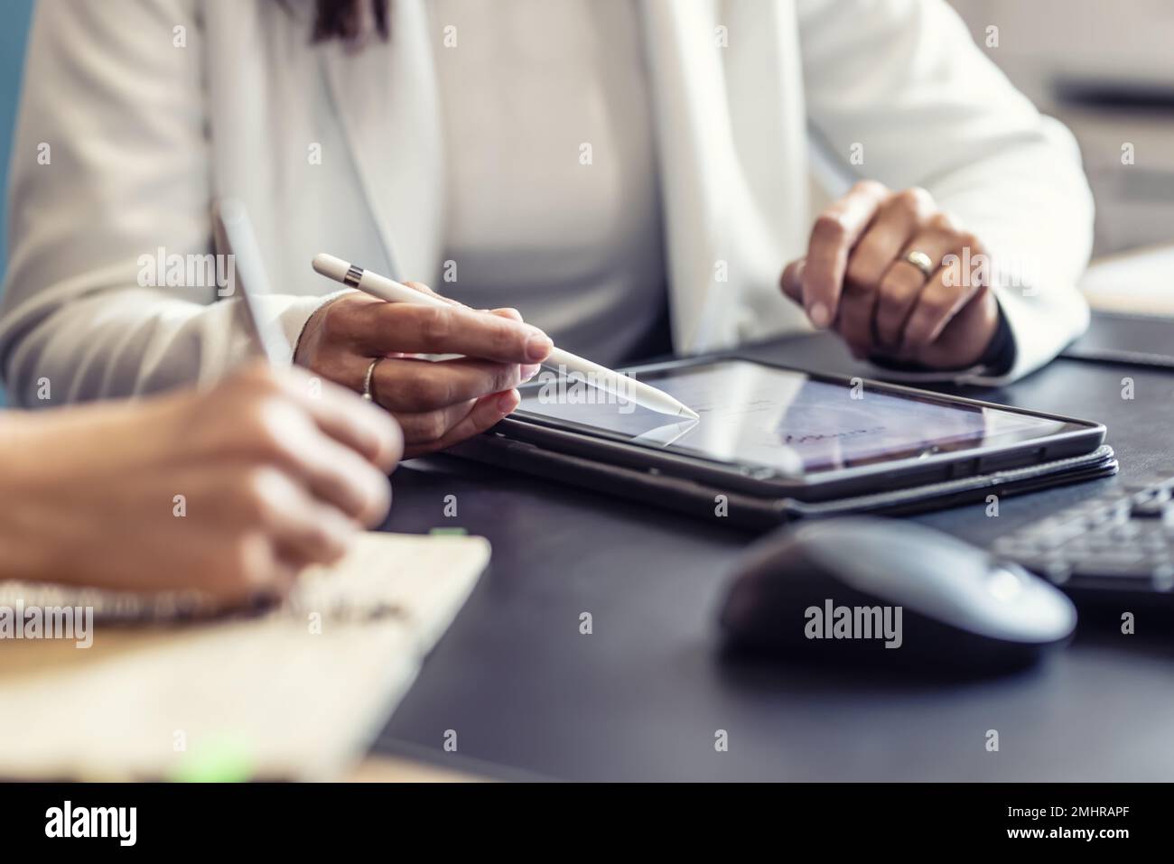 Le mani di due colleghi utilizzano un tablet digitale e un notebook. Un incontro d'affari per discutere di gestione finanziaria, contabilità o financ Foto Stock