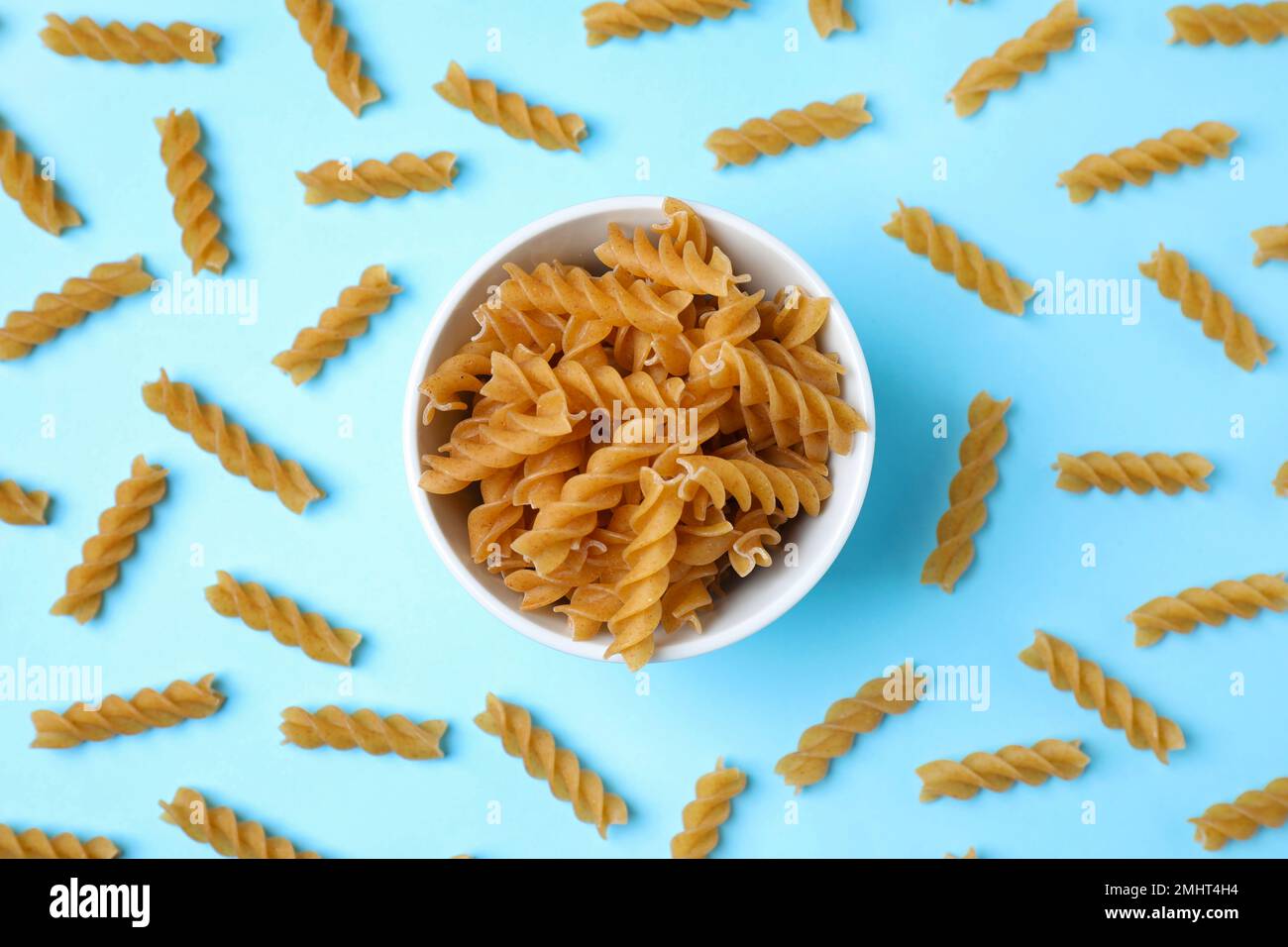 Composizione di posa piatta con pasta fusilli integrale su fondo azzurro Foto Stock