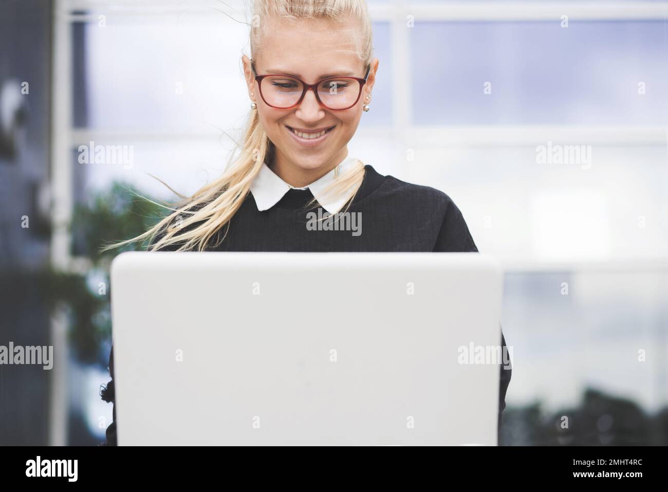 Giovane donna d'affari sorridente che lavora su un notebook. Foto Stock