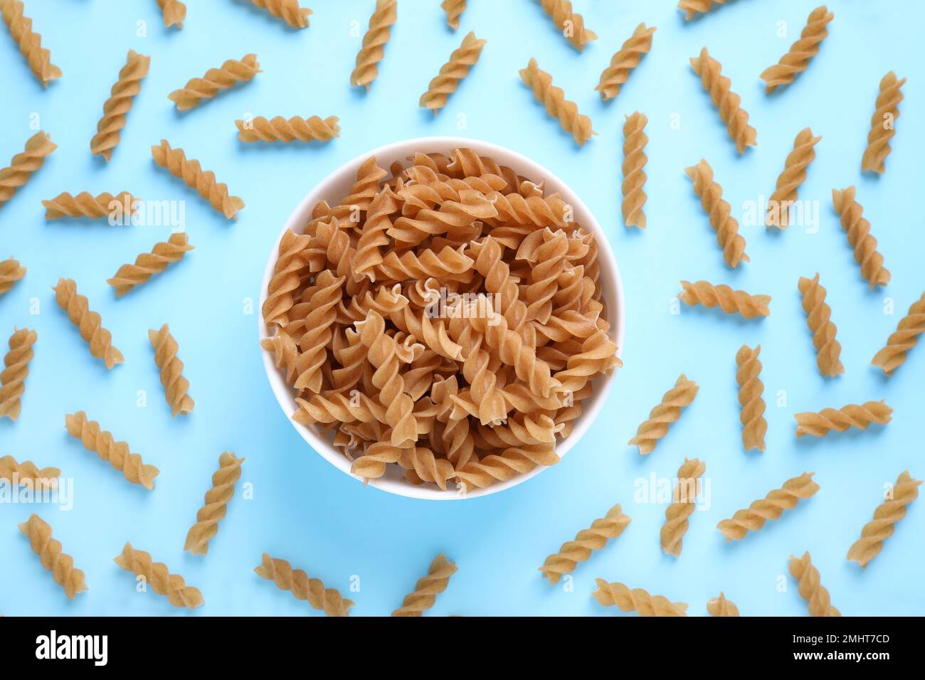 Composizione di posa piatta con pasta fusilli integrale su fondo azzurro Foto Stock