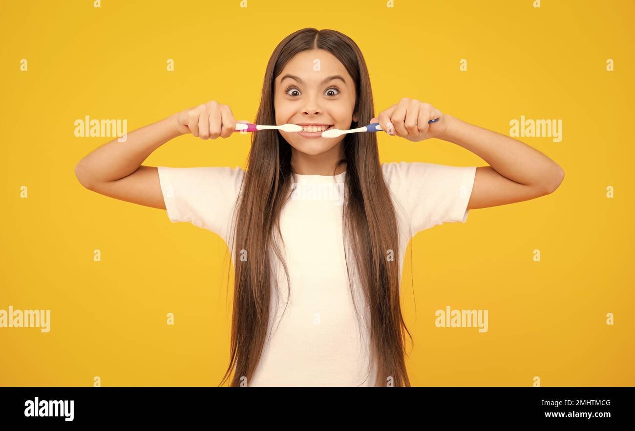 Faccia divertente. Ragazza teen divertente spazzolare i suoi denti, dentale sano concetto, isolato su sfondo giallo. Denti sani dei bambini. Medicina orale e stomatologia Foto Stock