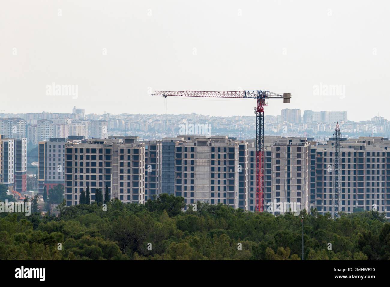 Grande gru da cantiere che lavora per la costruzione di abitazioni pubbliche in una giornata nuvolosa Foto Stock